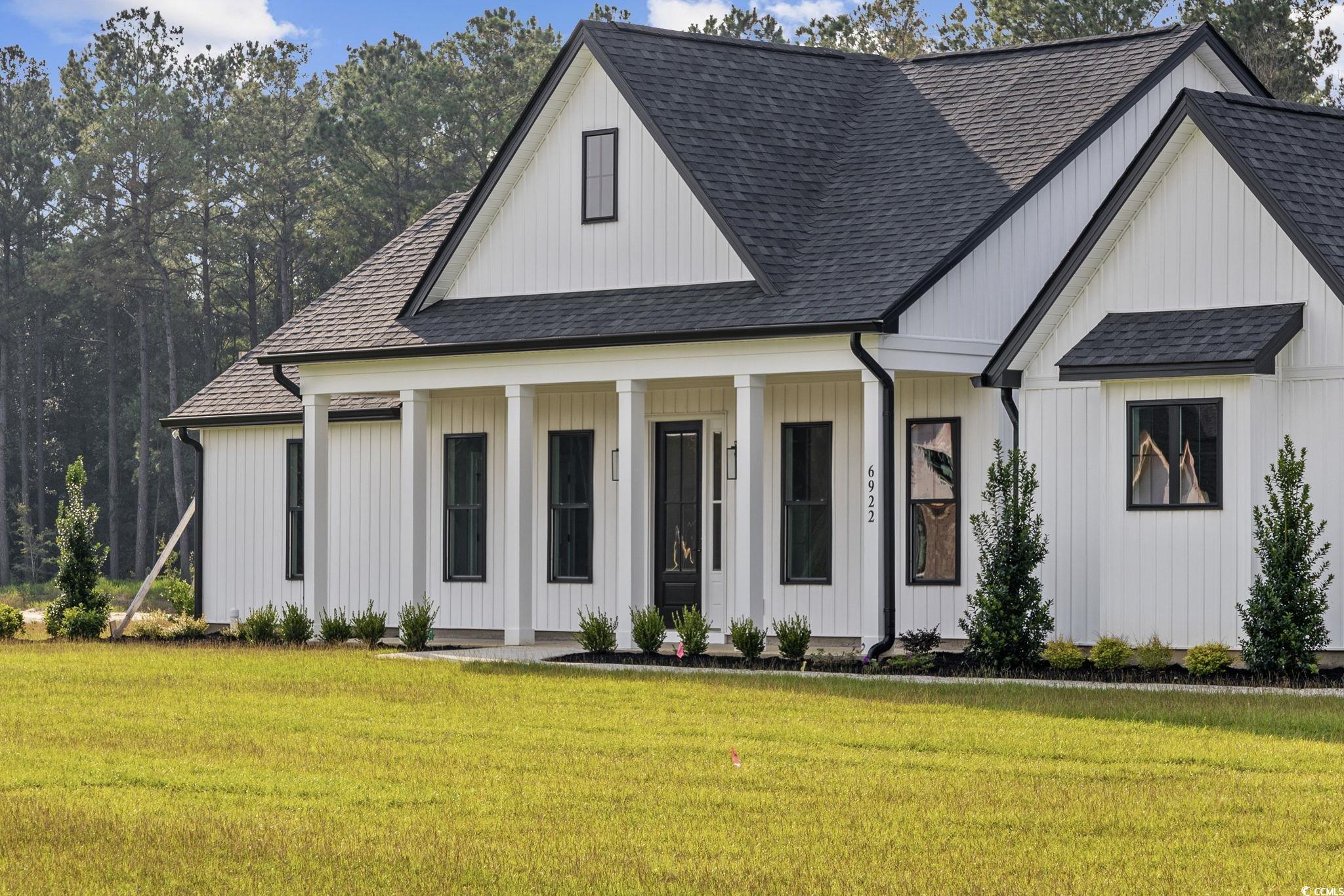 6922 Pauley Swamp Road Conway, SC 29527 - Photo 3 of 40 Modern farmhouse style home featuring roof with shingles, covered porch, and a front lawn