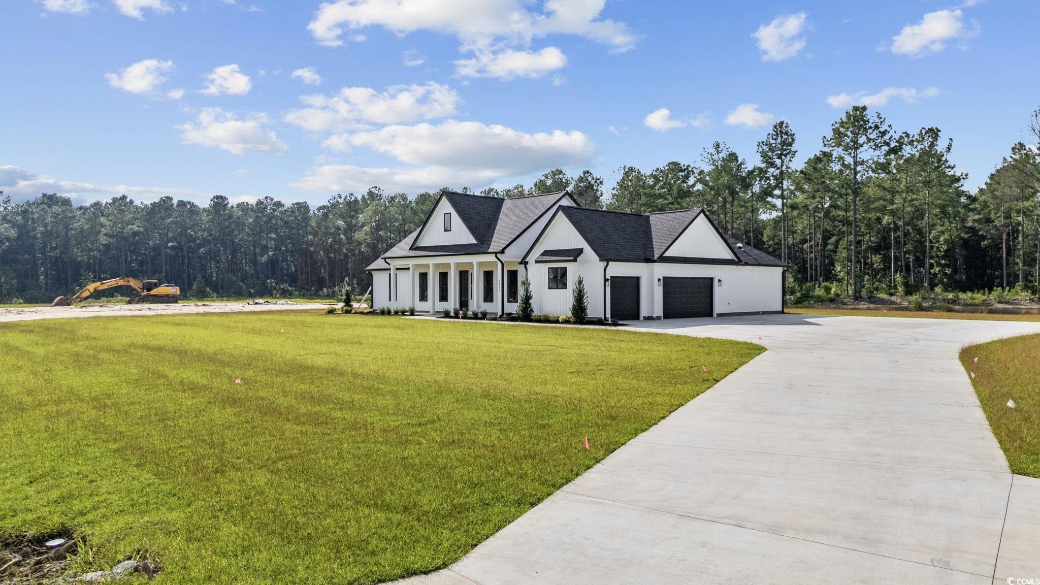 6922 Pauley Swamp Road Conway, SC 29527 - Photo 5 of 40 Modern farmhouse featuring driveway, a front lawn, a porch, an attached garage, and a wooded view