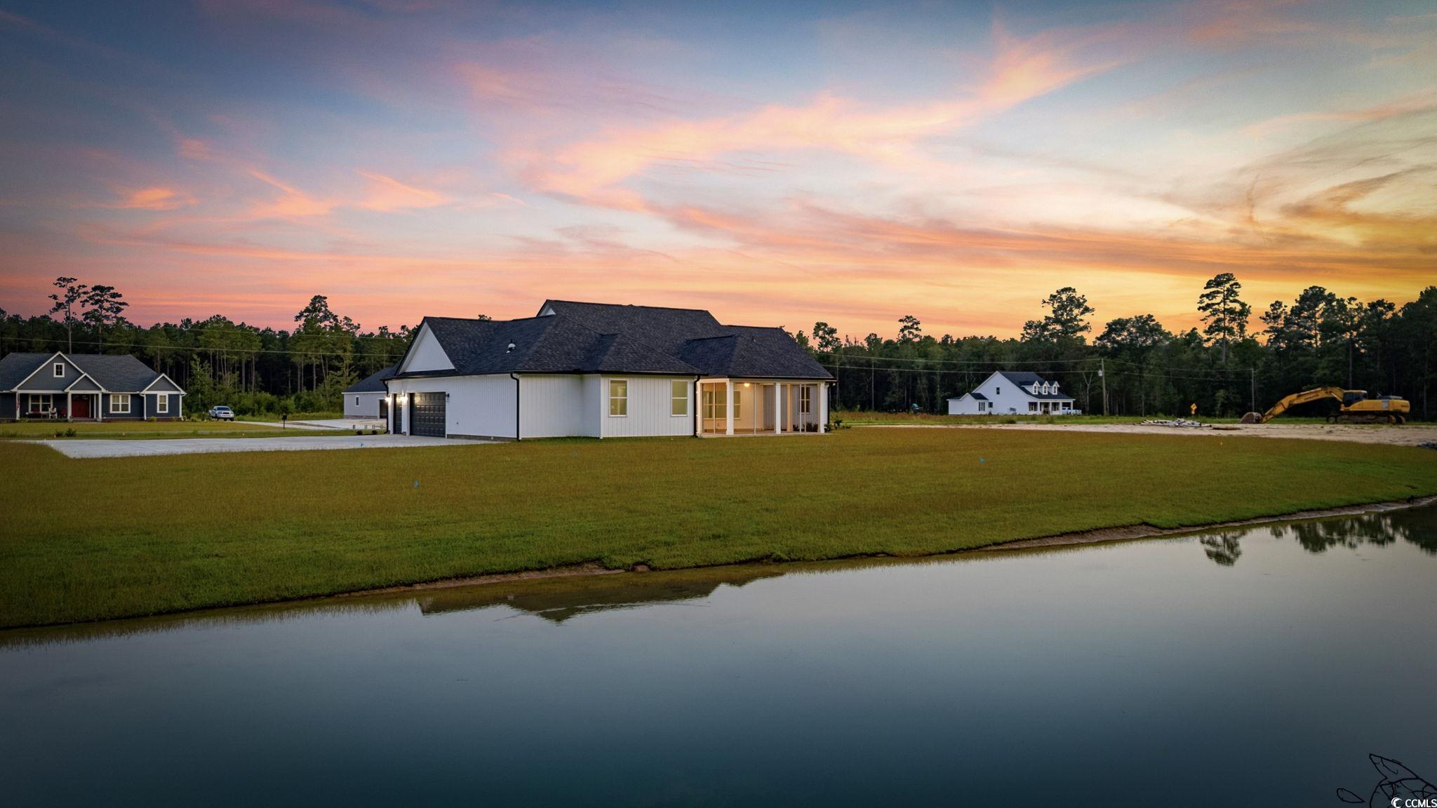 6922 Pauley Swamp Road Conway, SC 29527 - Photo 6 of 40 Back of house at dusk with a yard, an attached garage, a water view, and driveway