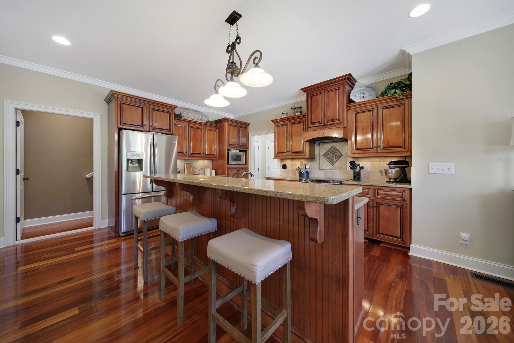 2407 Robert Usher Road Lancaster, SC 29720 - Photo 11 of 47 a kitchen with stainless steel appliances granite countertop a stove top oven a refrigerator a sink and dining table with wooden floor