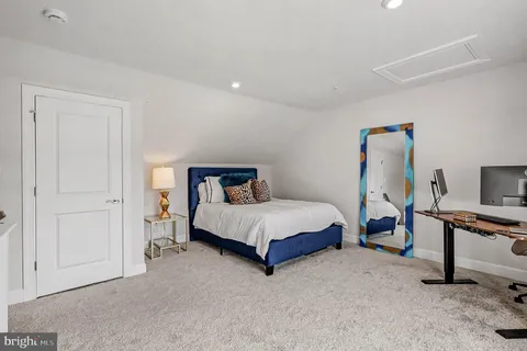 a spacious bedroom with a bed and a flat tv screen on wall