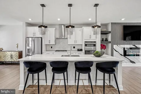 a kitchen with stainless steel appliances kitchen island granite countertop a dining table chairs and white cabinets