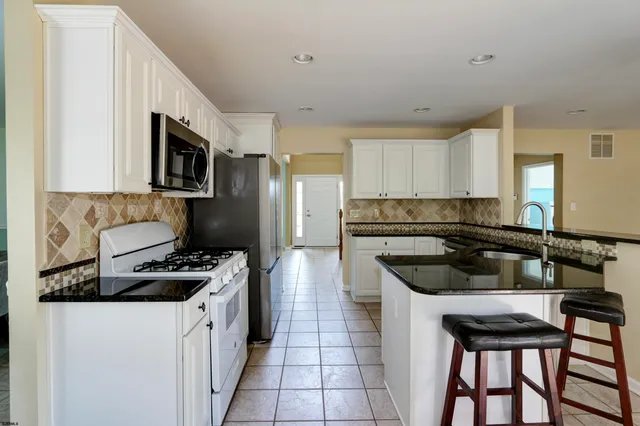 a kitchen with stainless steel appliances granite countertop a stove top oven a sink a dining table and chairs