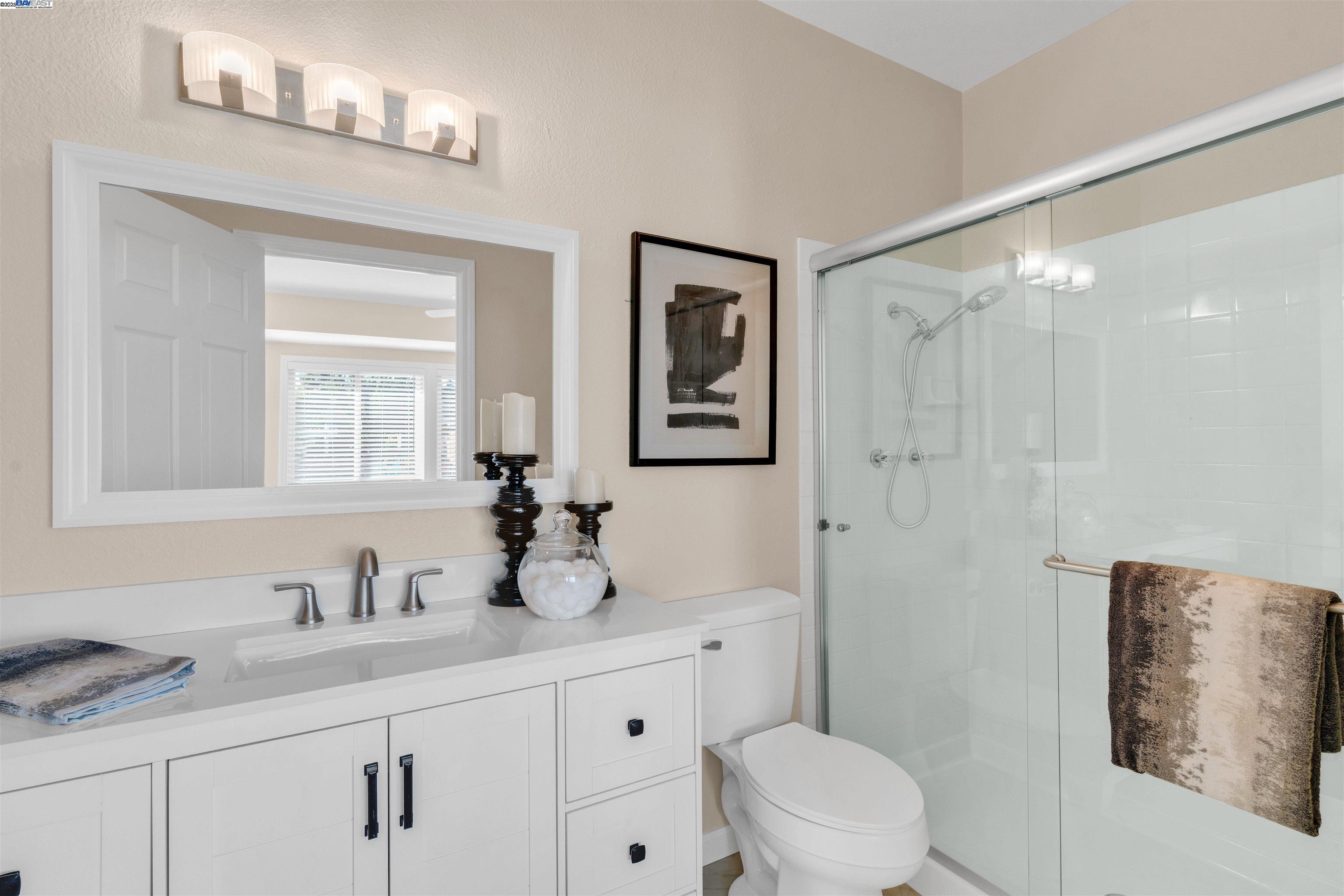 7602 Arbor Creek Circle Dublin, CA 94568 - Photo 28 of 47 a bathroom with a granite countertop sink a toilet and a mirror