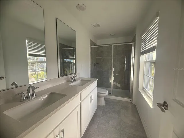 a bathroom with a double vanity sink toilet and shower