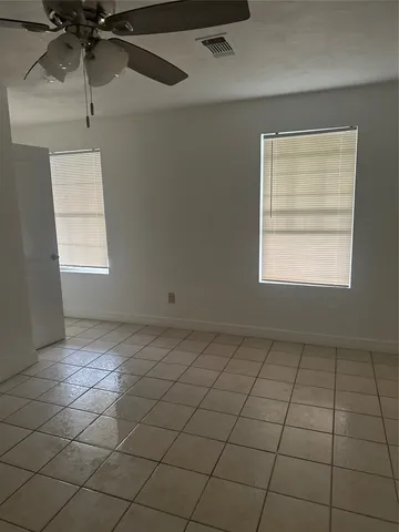 an empty room with windows and fan