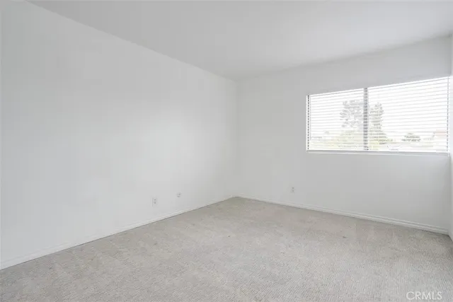 a view of an empty room with closet and a bathroom