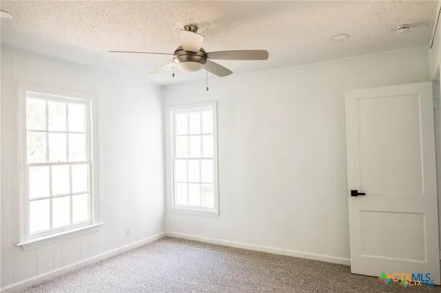 an empty room with windows and fan