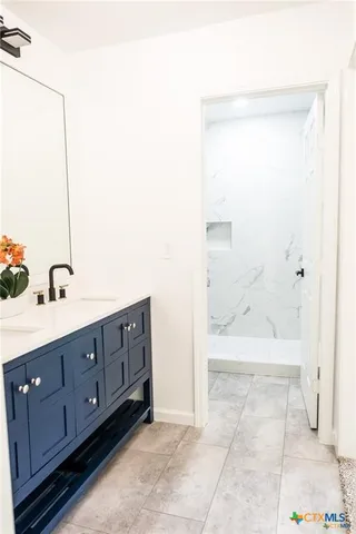 a bathroom with a double vanity sink a large mirror and a bathtub