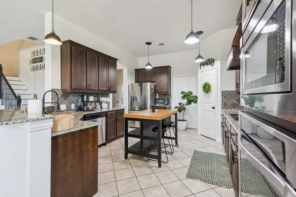 a kitchen with kitchen island granite countertop a sink counter top space appliances and cabinets
