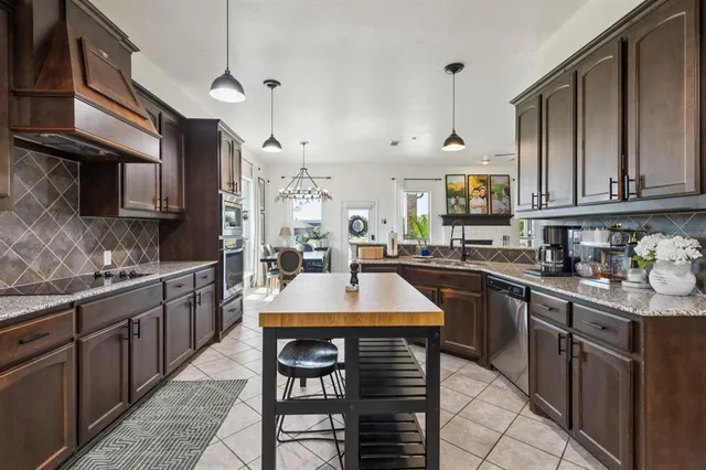 a kitchen with kitchen island granite countertop a sink a stove a oven a counter space and cabinets