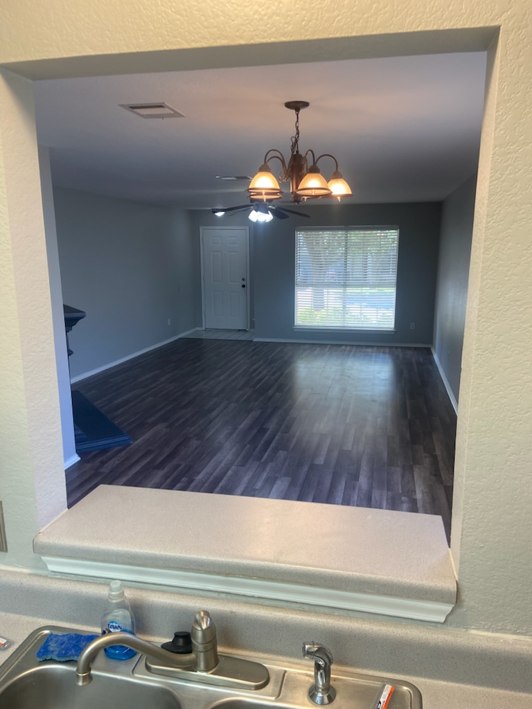 17616 Tobermory Drive Pflugerville, TX 78660 - Photo 13 of 14 A well-lit living area awaits, showcasing dark plank flooring and a classic chandelier.