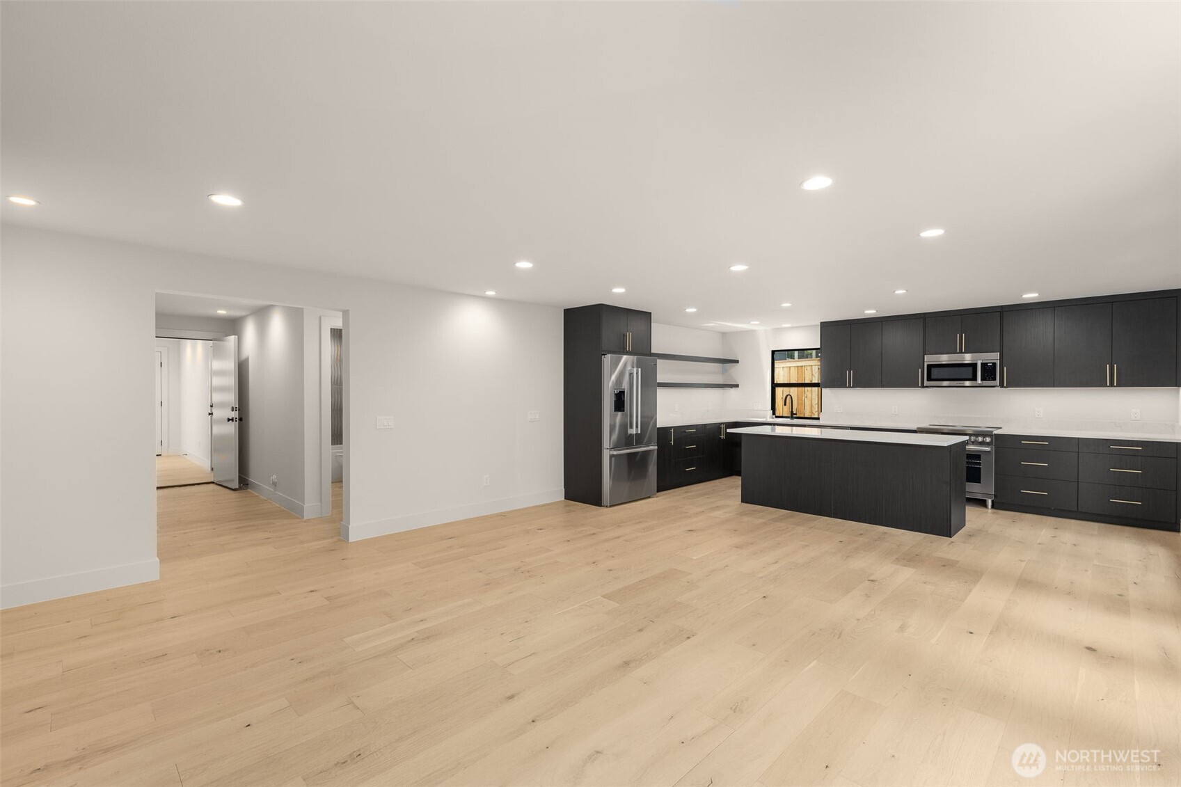 6833 36th Avenue Northeast Seattle, WA 98115 - Photo 25 of 40 a large white kitchen with kitchen island a sink dishwasher a refrigerator and a oven with wooden floor