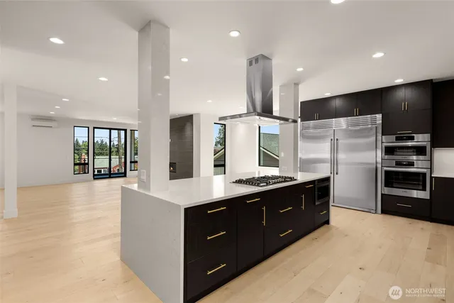 a large kitchen with stainless steel appliances a large counter top a stove and a refrigerator