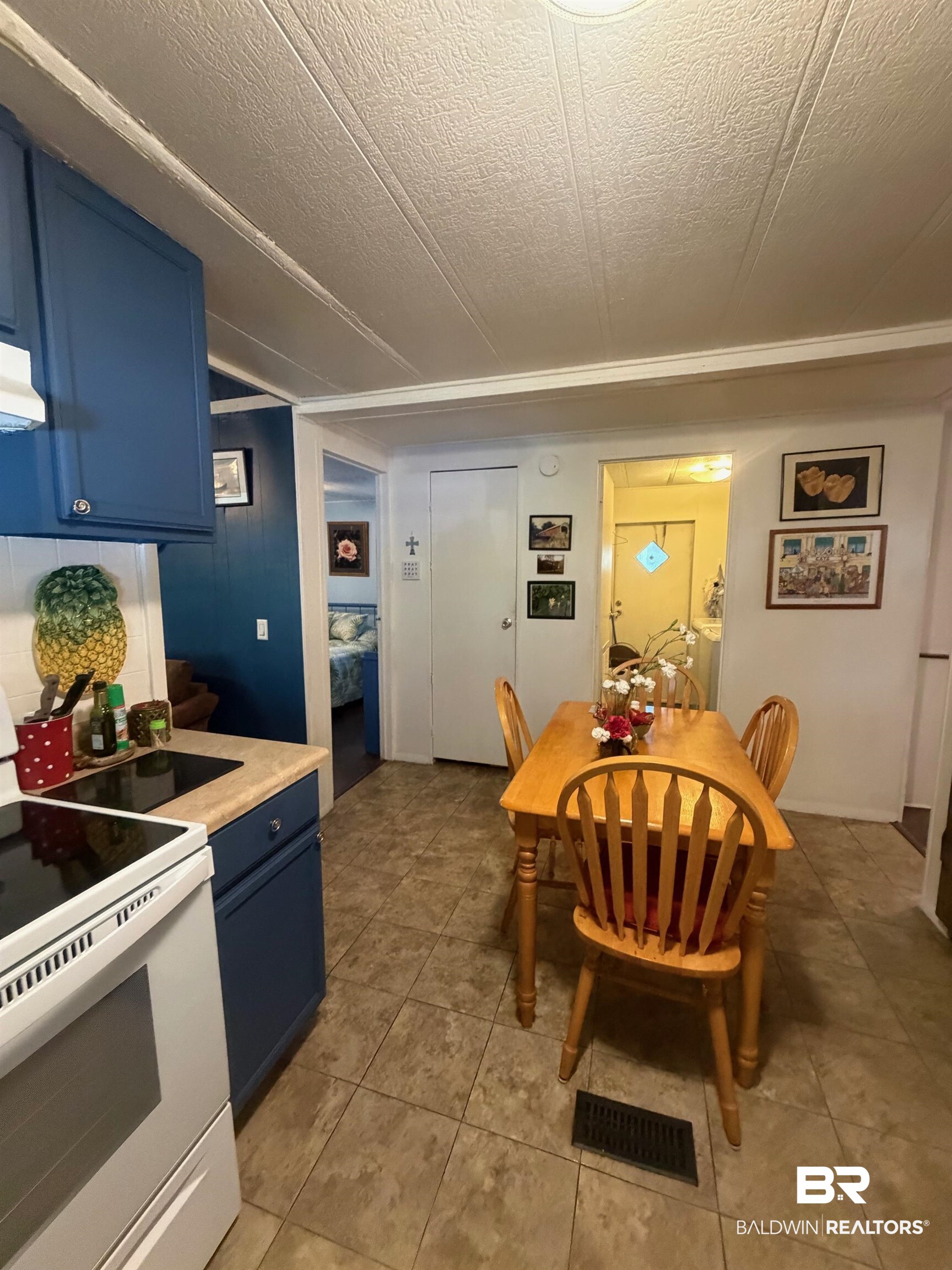 1430 Ridgewood Drive Lillian, AL 36549 - Photo 8 of 34 Kitchen featuring blue cabinets, white electric range, a textured ceiling, and light tile patterned flooring