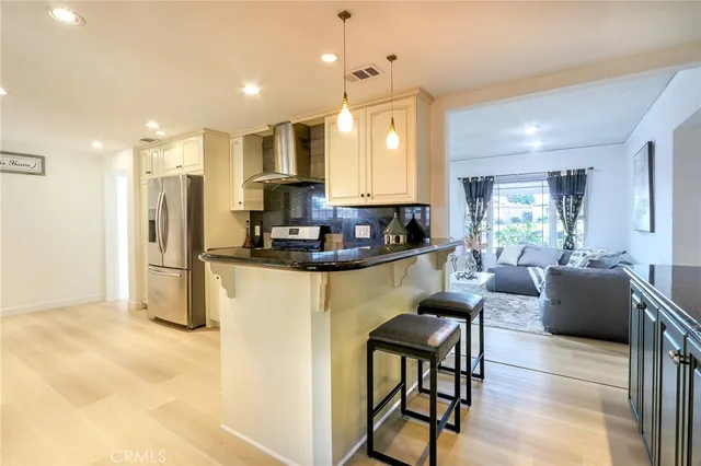 a kitchen with stainless steel appliances granite countertop a refrigerator a stove a sink dishwasher and white cabinets with wooden floor