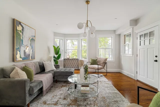 a living room with furniture two window and a wooden floor