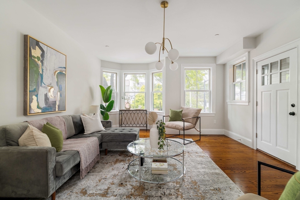 a living room with furniture two window and a wooden floor