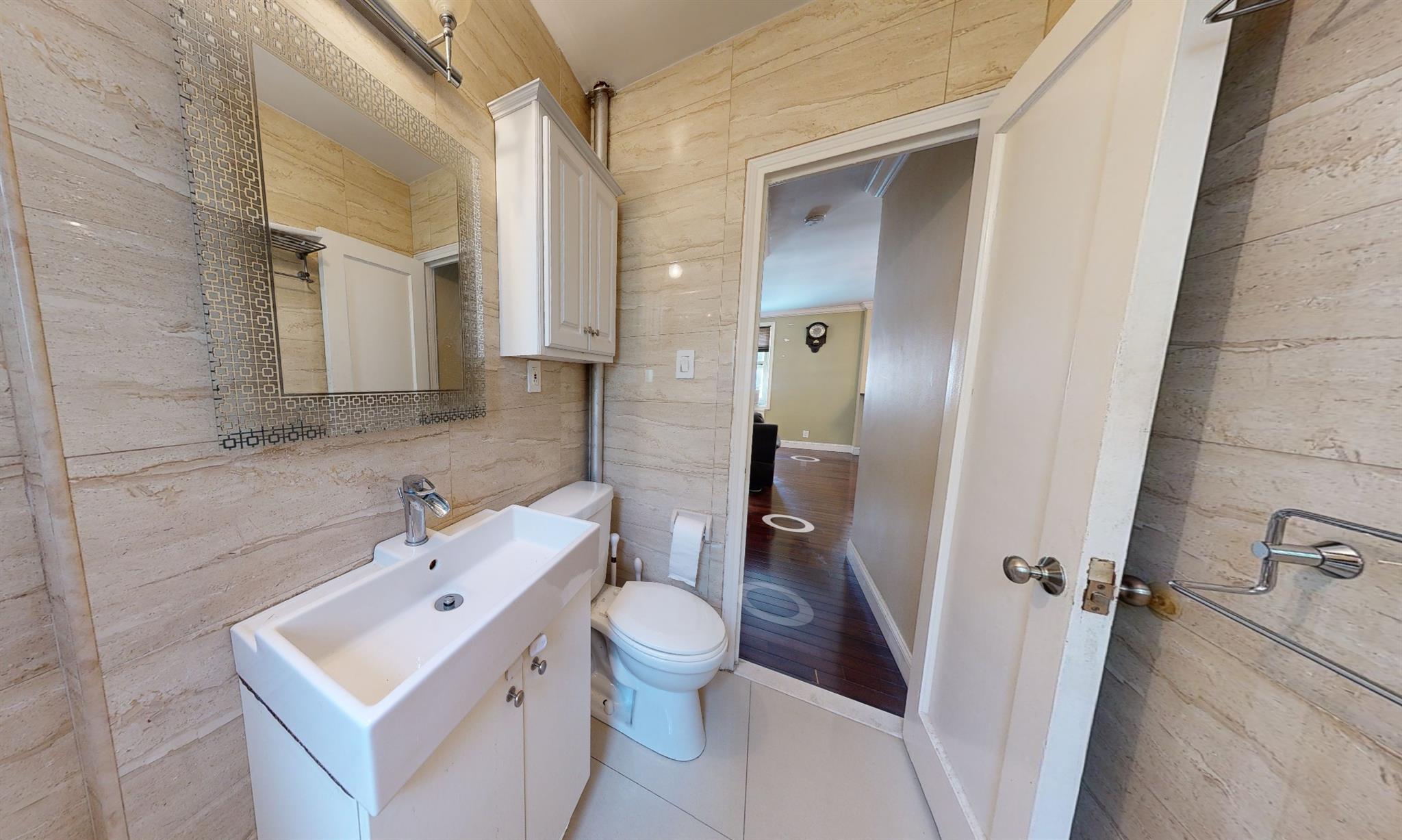 94-10 64th Road, Unit B6 Queens, NY 11374 - Photo 13 of 17 Bathroom featuring toilet, vanity, and tile walls