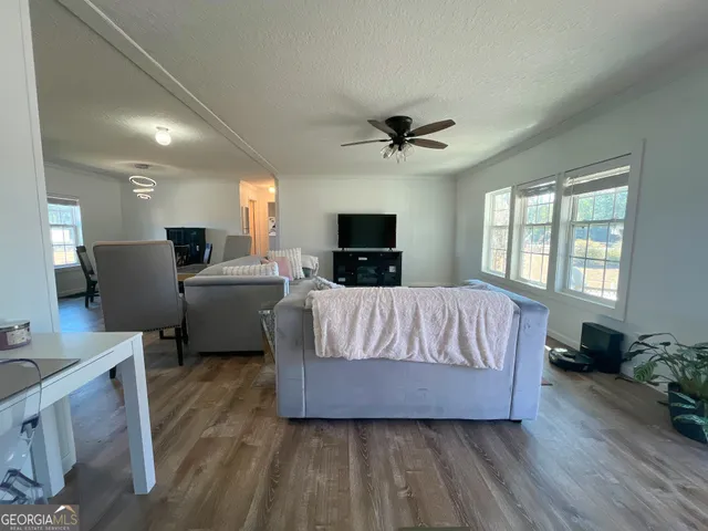 a living room with a bed furniture flat screen tv and window
