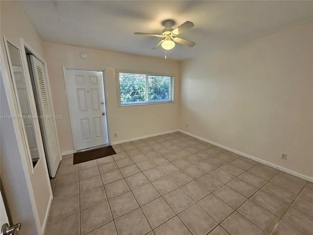 an empty room with windows and chandelier fan