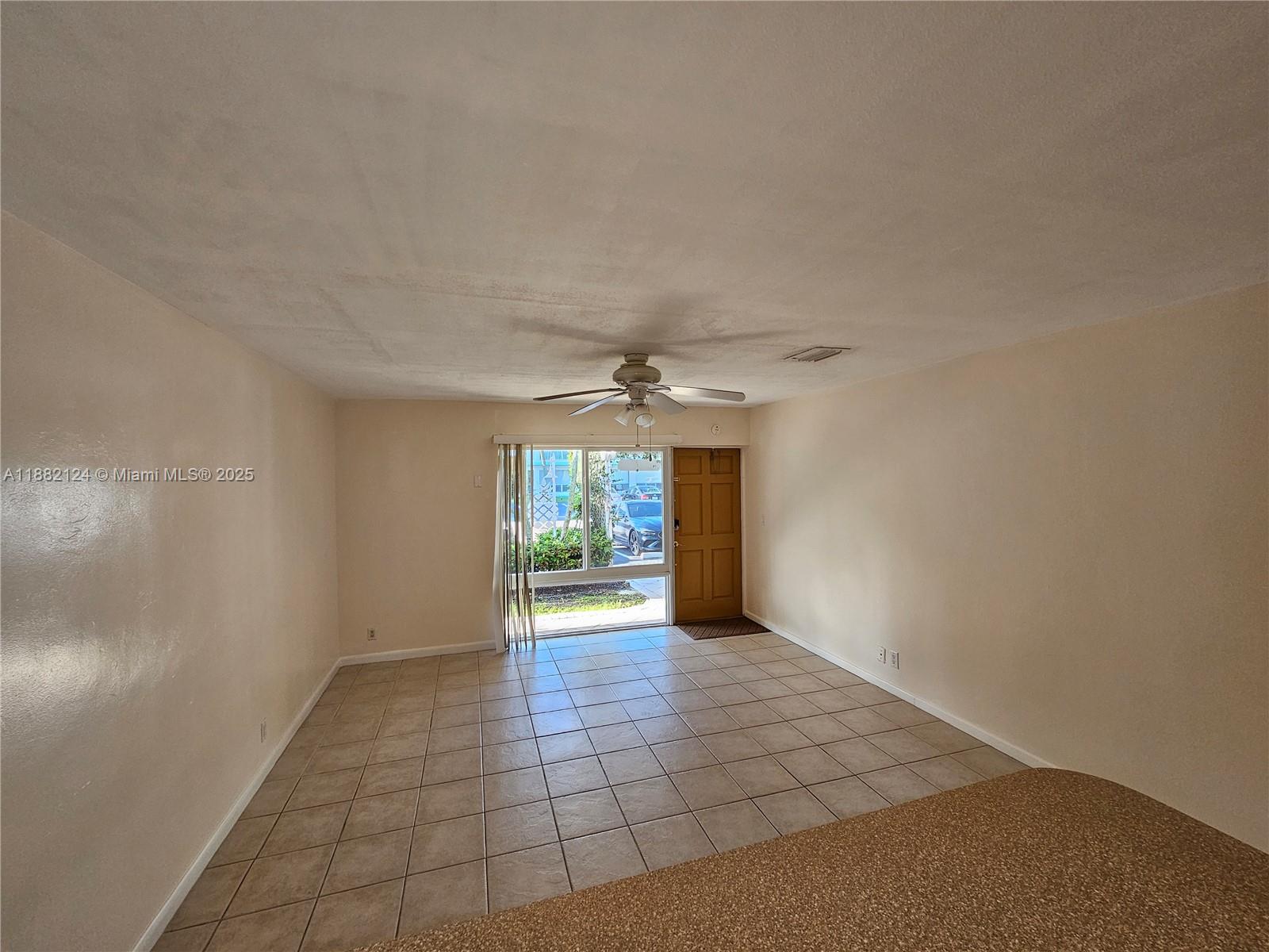 3217 Northeast 7th Place, Unit 2 Pompano Beach, FL 33062 - Photo 18 of 20 an empty room with windows and chandelier fan