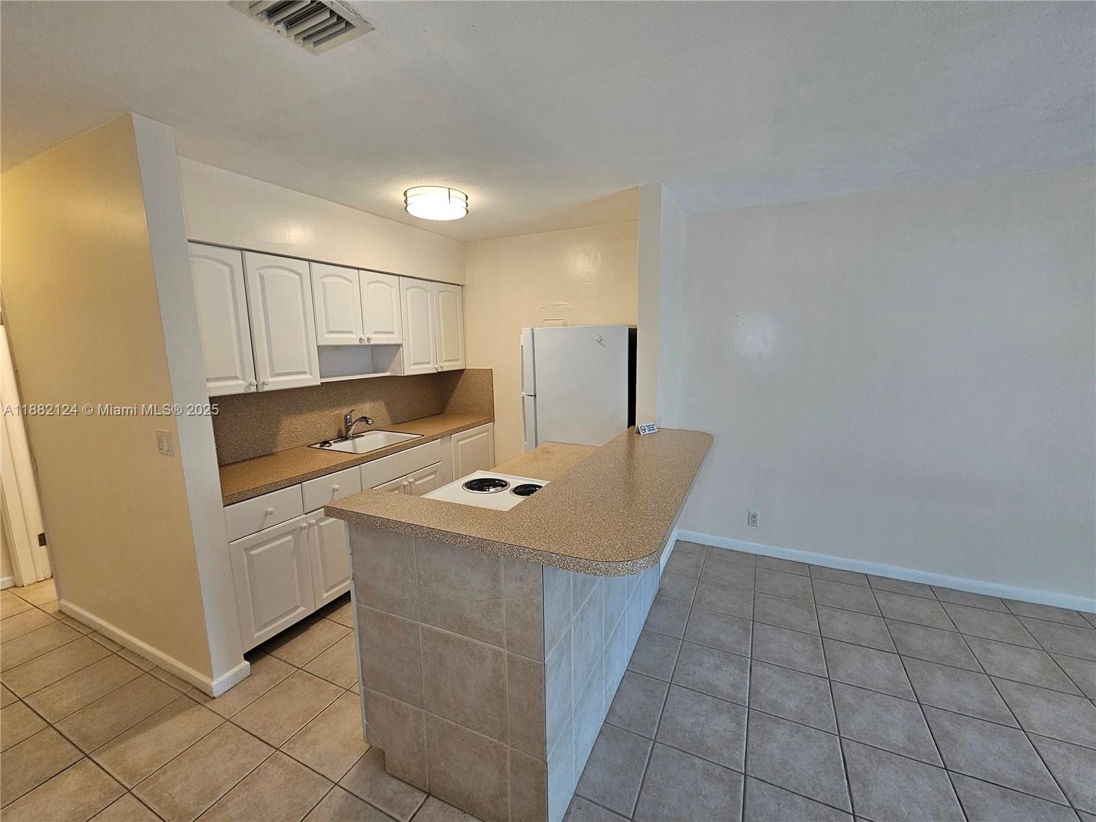 3217 Northeast 7th Place, Unit 2 Pompano Beach, FL 33062 - Photo 10 of 20 a kitchen with a sink appliances and cabinets