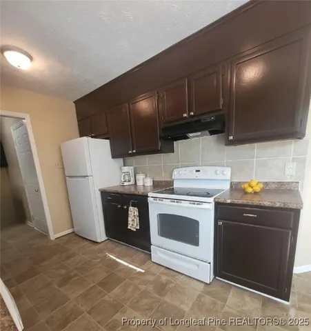 a kitchen with stainless steel appliances a stove a refrigerator a sink a stove with wooden floor