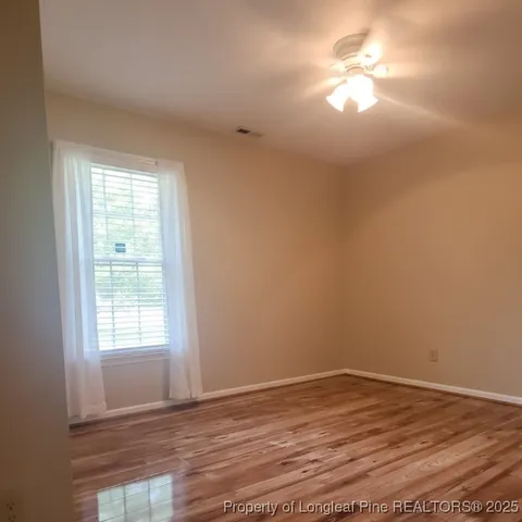 a view of empty room with wooden floor and fan