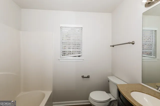 a white toilet sitting next to a bathroom sink and vanity