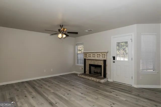 an empty room with wooden floor a fireplace and windows