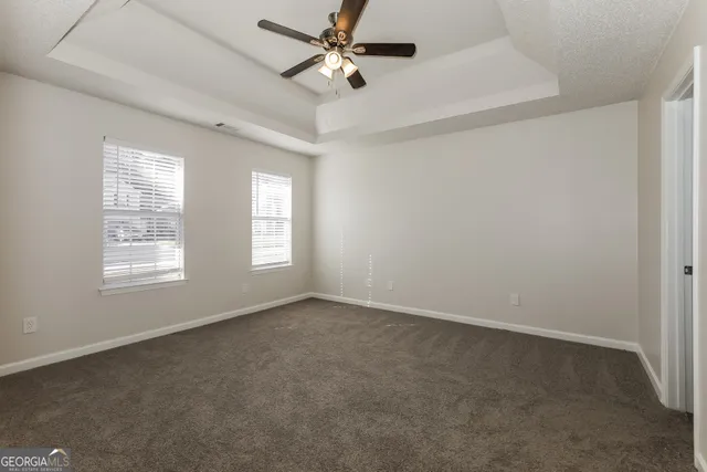 an empty room with windows and fan