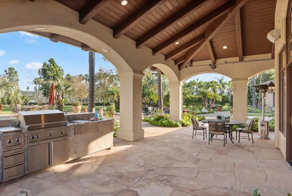 15611 Via De Santa Fe Rancho Santa Fe, CA 92067 - Photo 19 of 25 a view of a patio with couches chairs potted plants and palm trees
