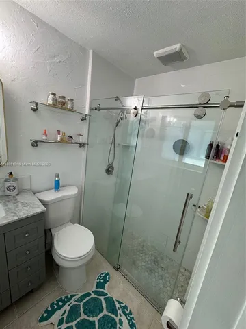 a bathroom with a granite countertop toilet a sink and shower