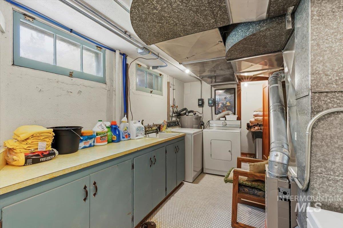 4619 Freemont Street Boise, ID 83706 - Photo 14 of 27 Dedicated utility space featuring a long countertop, blue-painted cabinetry, two windows, wall-mounted lighting, and a white hexagonal tile floor