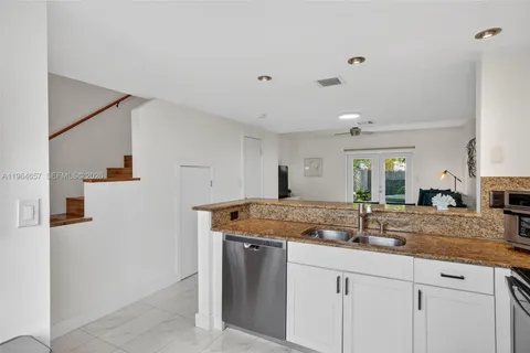 a kitchen with stainless steel appliances granite countertop a sink and dishwasher with white cabinets