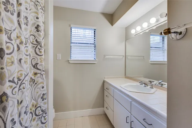 a bathroom with a granite countertop sink a mirror and a shower curtain