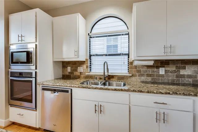 a kitchen with granite countertop white cabinets and stainless steel appliances