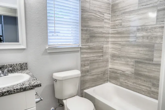 a bathroom with a granite countertop toilet sink and mirror