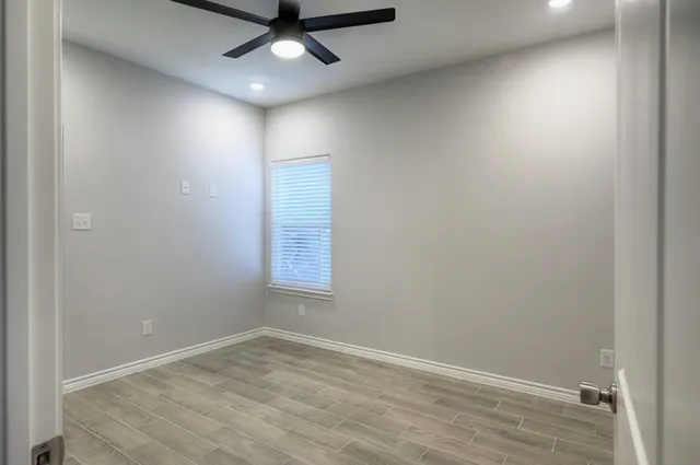 an empty room with a window and a ceiling fan
