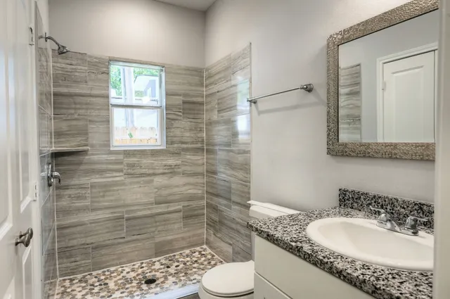 a bathroom with a granite countertop sink toilet and shower