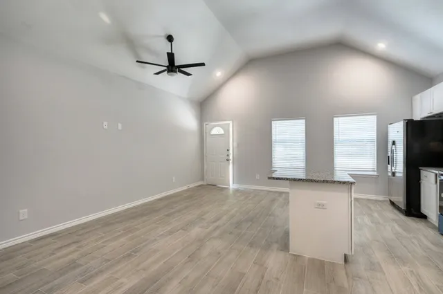 an empty room with windows and a ceiling fan