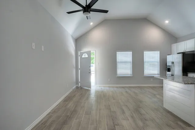 an empty room with wooden floor and windows
