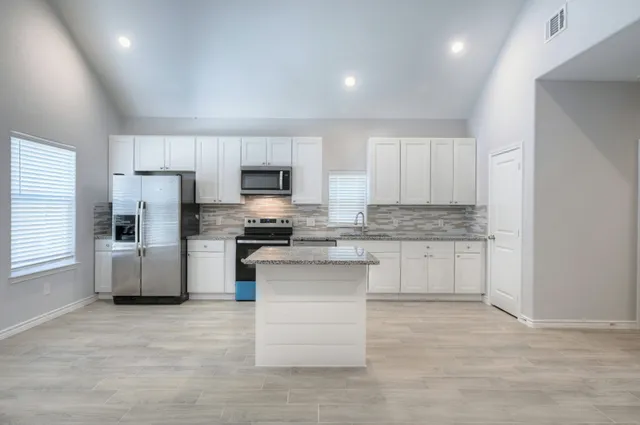 a kitchen with white cabinets and stainless steel appliances