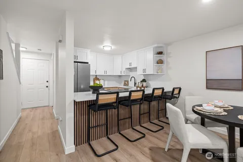 a kitchen with stainless steel appliances granite countertop a dining table chairs refrigerator sink and cabinets