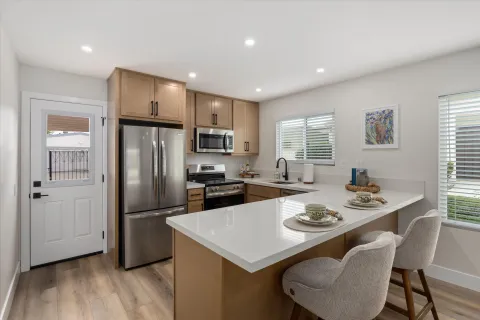 a kitchen with refrigerator and wooden floor