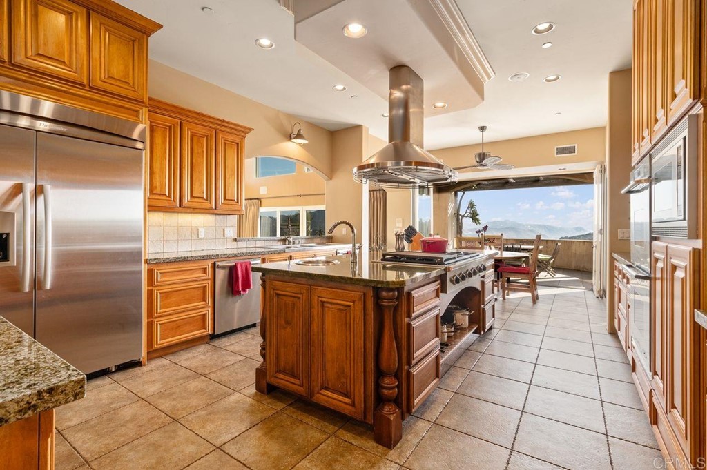 10363 Hidden Meadows Road Escondido, CA 92026 - Photo 18 of 65 a kitchen with stainless steel appliances kitchen island granite countertop a large counter top a stove a chimney a sink and a refrigerator