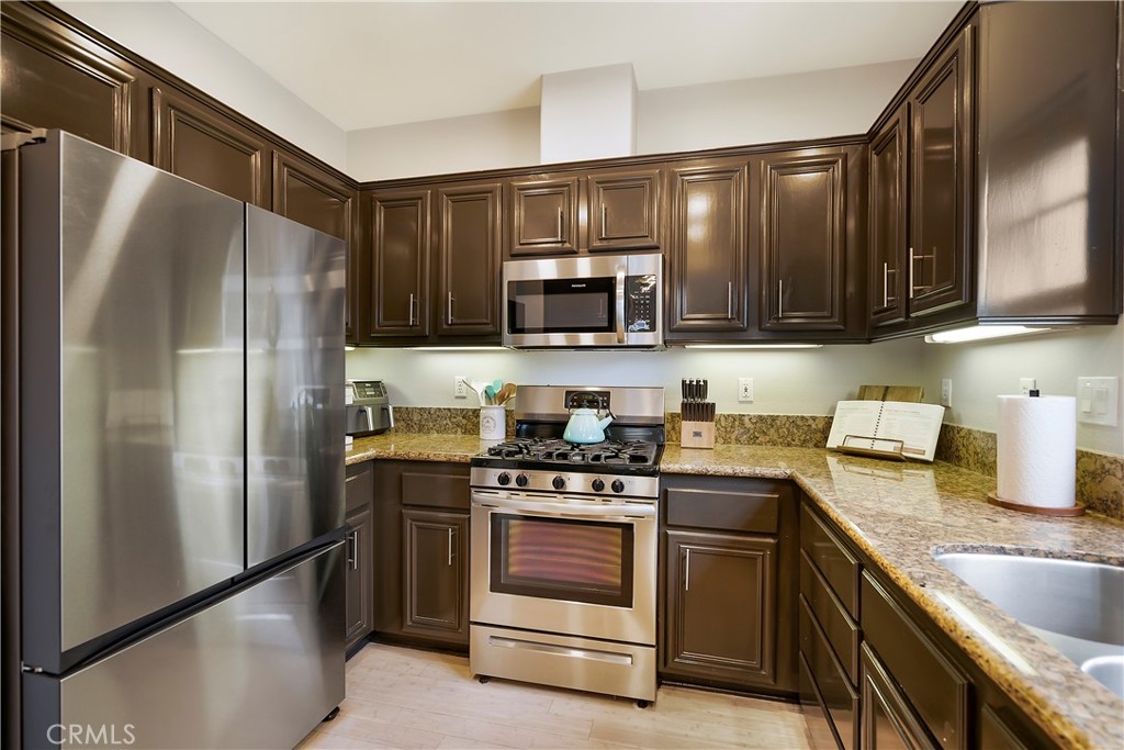 60 Strawflower Street Ladera Ranch, CA 92694 - Photo 11 of 34 a kitchen with granite countertop a refrigerator stove and microwave