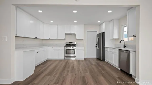 a kitchen with white cabinets stainless steel appliances and window