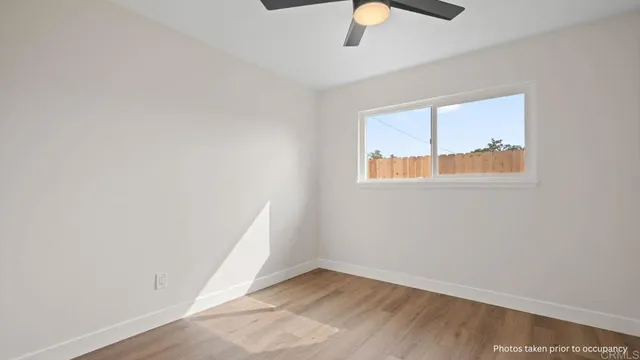 an empty room with a window and ceiling fan
